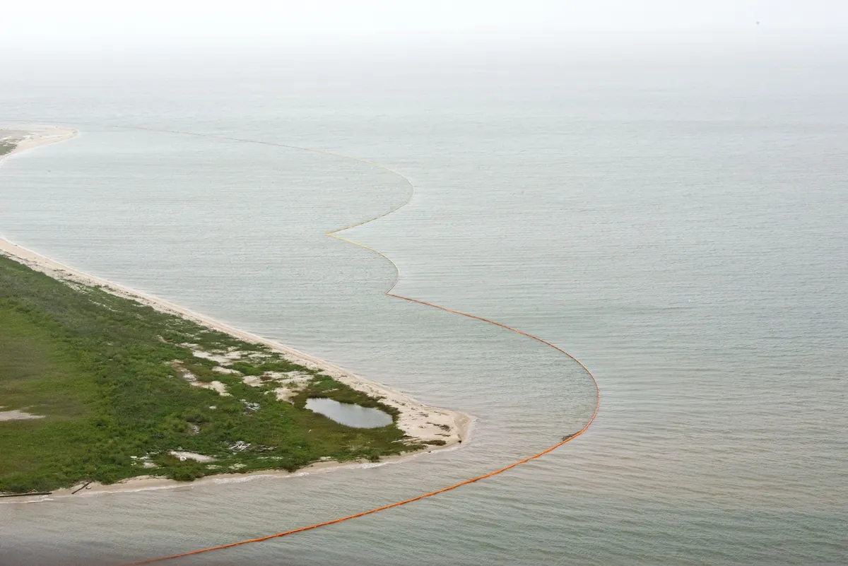 Aerial view of a containment boom laid along a low coastline
