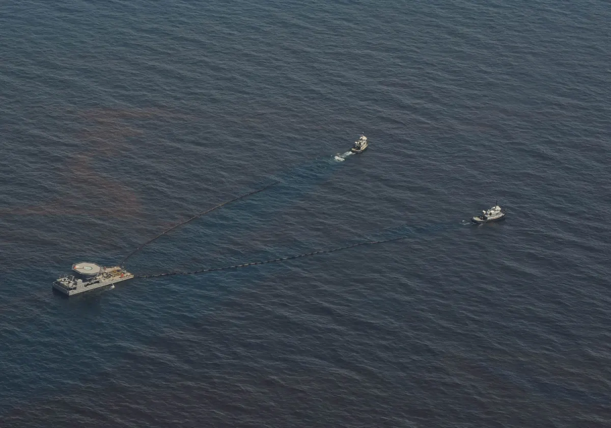 Aerial view of skimming vessels towing a boom through brown oil